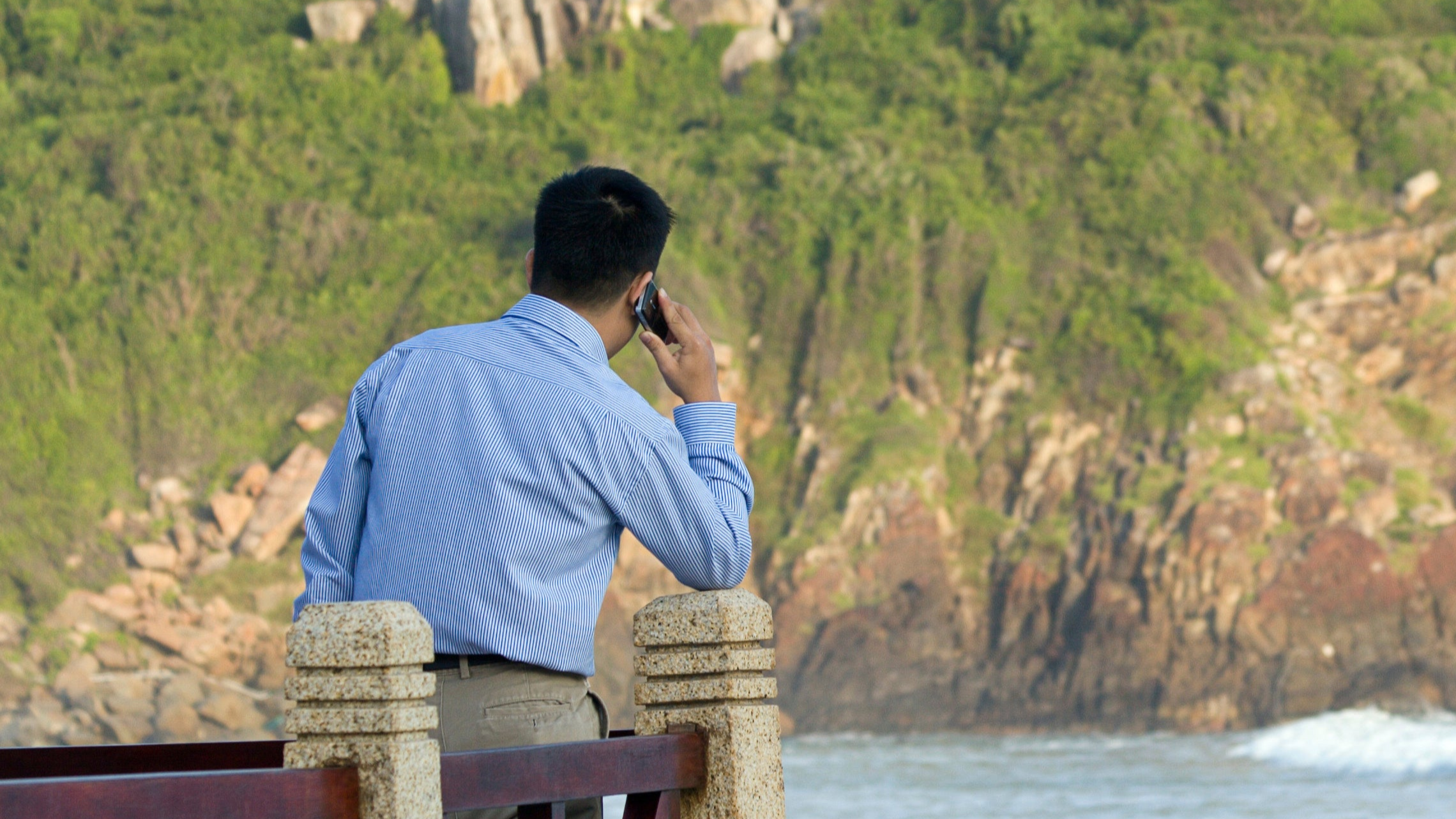 Businessman on phone overlooking water.