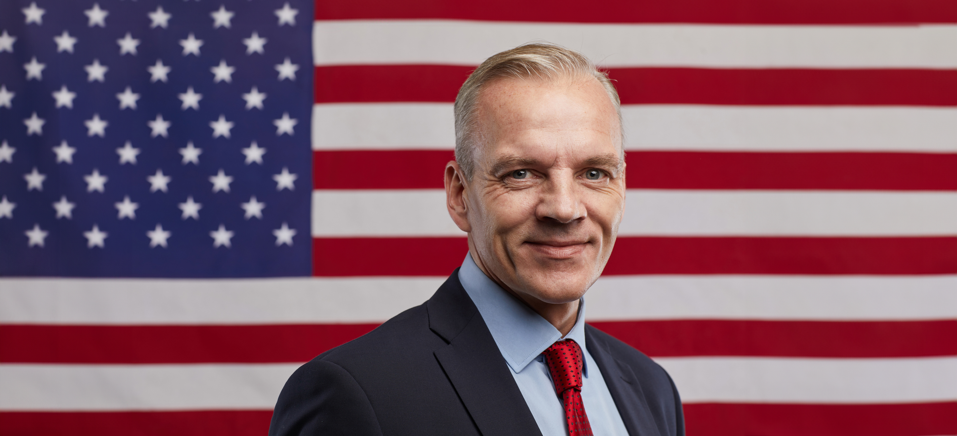 Businessman standing in front of US flag.